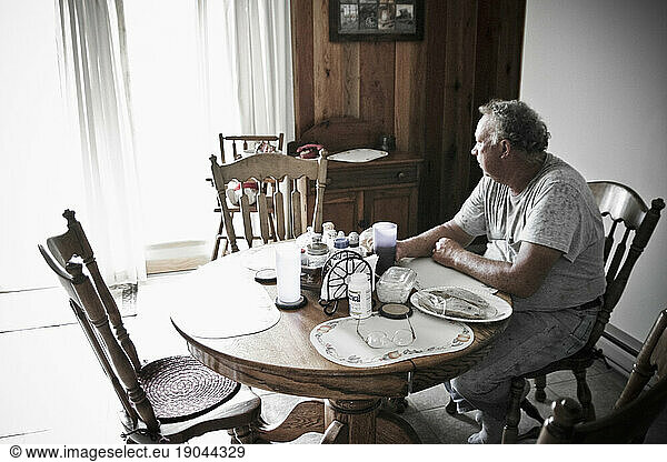 An older man looks out the window from his farm house kitchen before lunch in Keymar  Maryland.