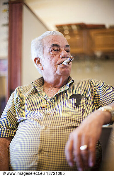 An older man relaxes and smokes a cigar.