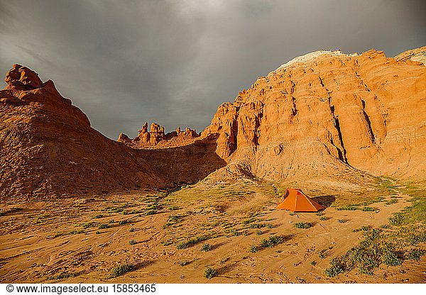 an orange tent sits at the base of red sandstone formations in utah