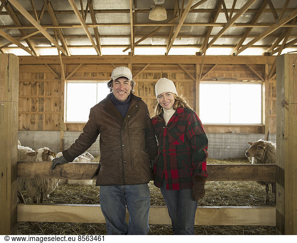 An Organic Farm in Winter in Cold Spring  New York State. A farmer and a woman standing by a pen full of sheep.