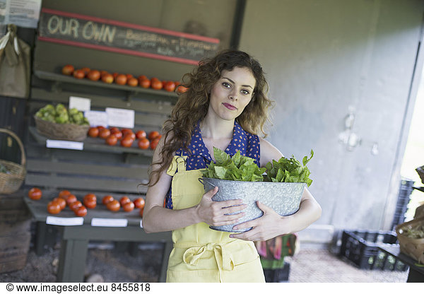 An organic farm stand. A woman sorting vegetables.
