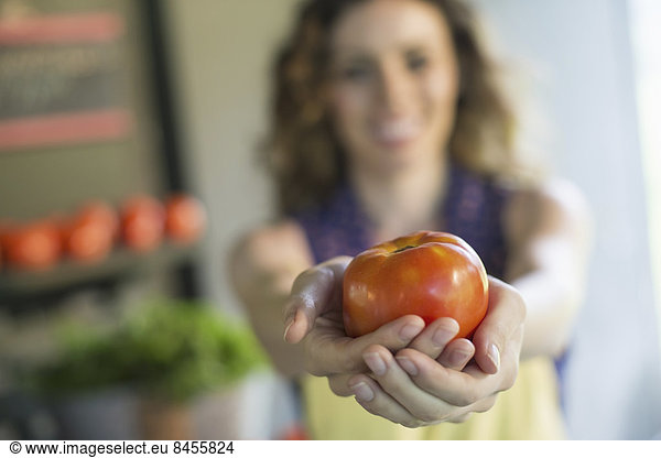 An organic fruit and vegetable farm. A woman holding a tomato.