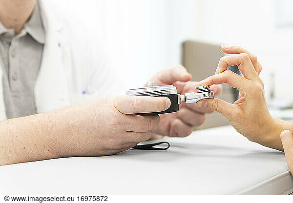 an orthopedist assesses the strength of the fingers of one hand