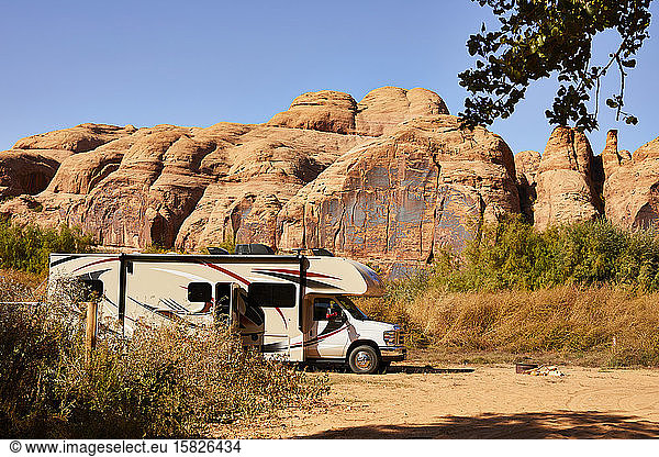 An RV parked in front of a red rock wall in Moab  Utah.