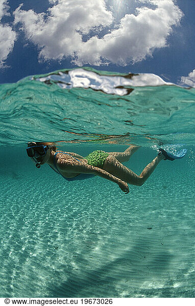 An underwater view of a woman snorkeling in the Bahamas.