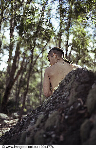 Androgynous topless woman looks over shoulder in nature