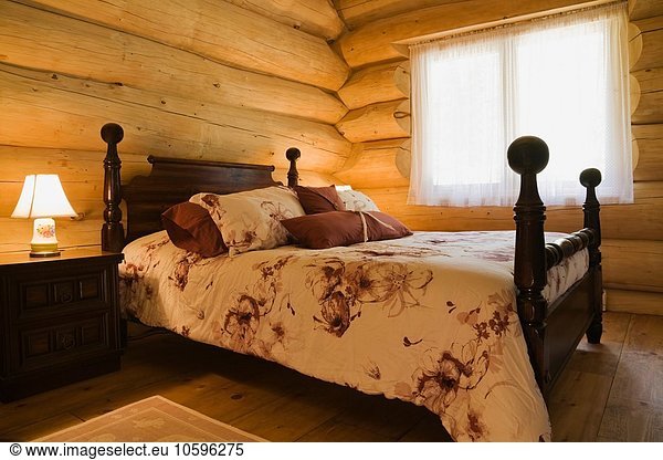 Angled view of antique wooden bed in Eastern white wood log cabin