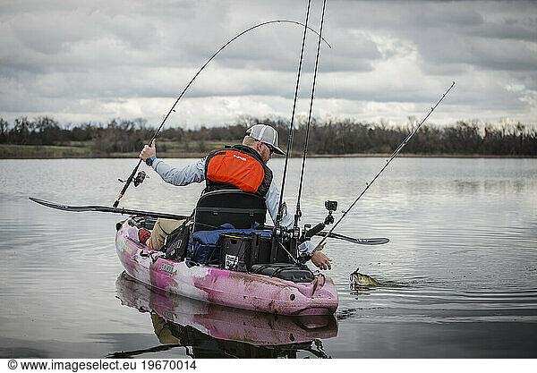 Angler catches a large mouth bass in a pink yak