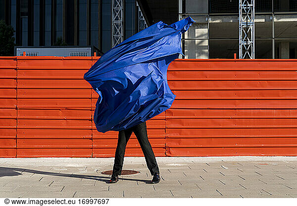 Anonymous man covered by blue cape