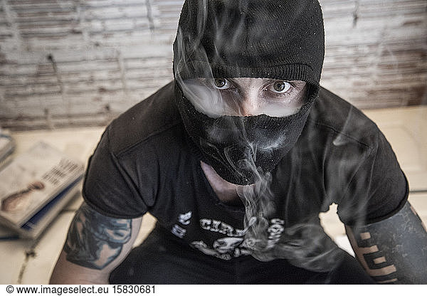 Anonymous punk activist smoking and wearing a balaclava