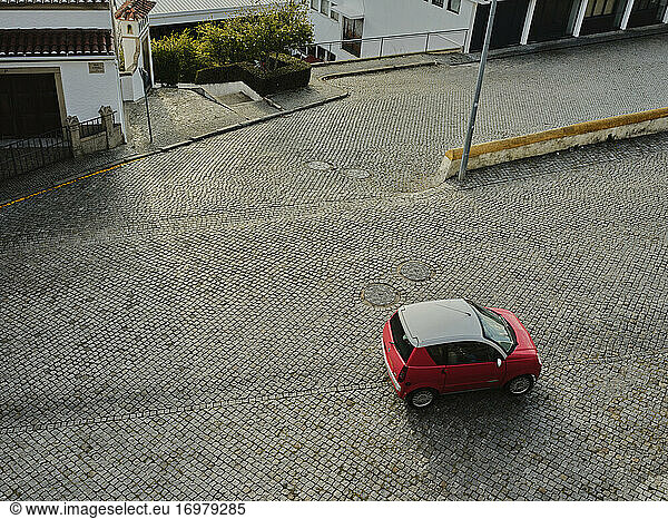 Ansicht von oben auf kompakte rote Auto fahren auf Kopfsteinpflaster Straße