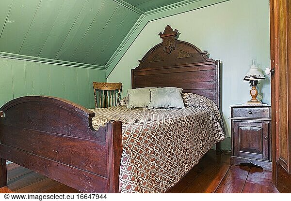 Antikes Doppelbett mit hölzernem Kopf- und Fußteil  Nachttisch und Schaukelstuhl im Gästezimmer im Obergeschoss eines alten Hauses im kanadischen Stil um 1840  Quebec  Kanada. Dieses Bild ist freigegebenes Eigentum. CUPR0361.