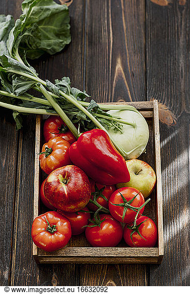 Apfel Kohlrabi Tomaten und rote Paprikaschote in Holzkiste