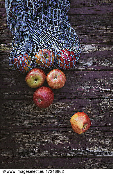 Apples with mesh bag on wooden table