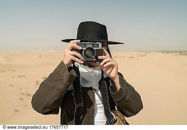 Arabic female traveler taking photos with film camera in the des