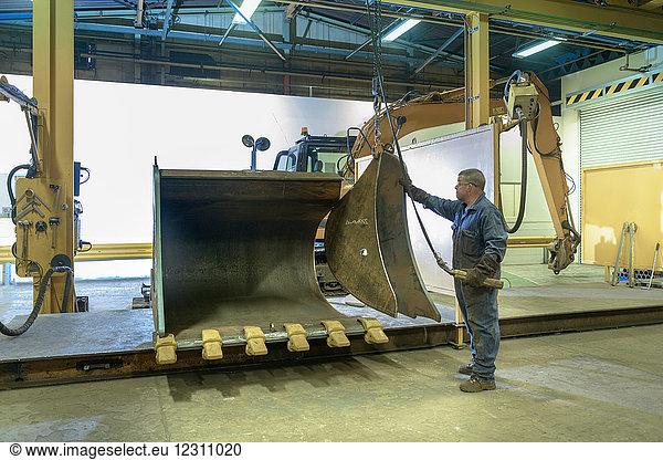 Arbeiter beim Zusammenbau einer Baggerschaufel in einer Maschinenfabrik