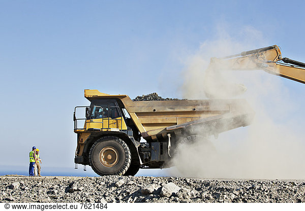 Arbeiter  die Bagger und Lkw im Steinbruch beaufsichtigen