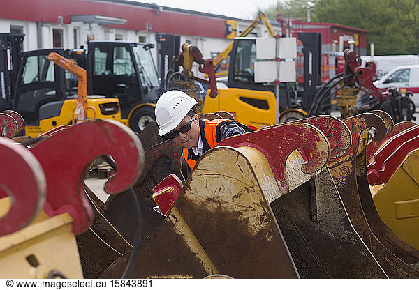 Arbeiter mit Helm zwischen Kränen