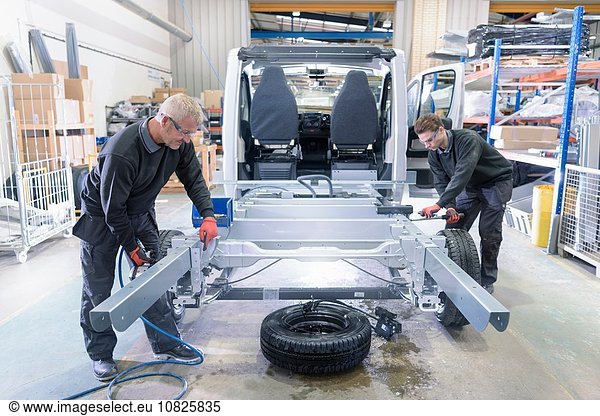 Arbeiter montieren Fahrgestelle an Reisemobil-Produktionslinie