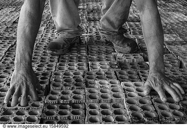 Arbeiter pickt Ziegelsteine in einem Ziegelwerk