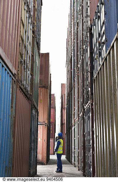 Arbeiter steht zwischen Frachtcontainern