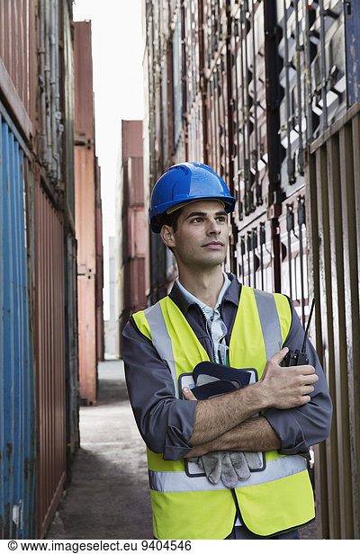 Arbeiter steht zwischen Frachtcontainern