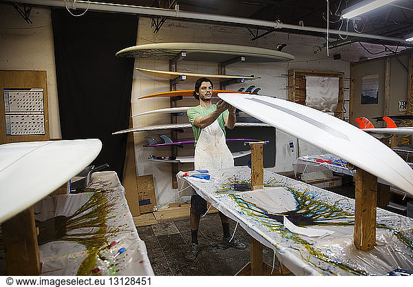 Arbeiter untersucht Surfbrett in Werkstatt