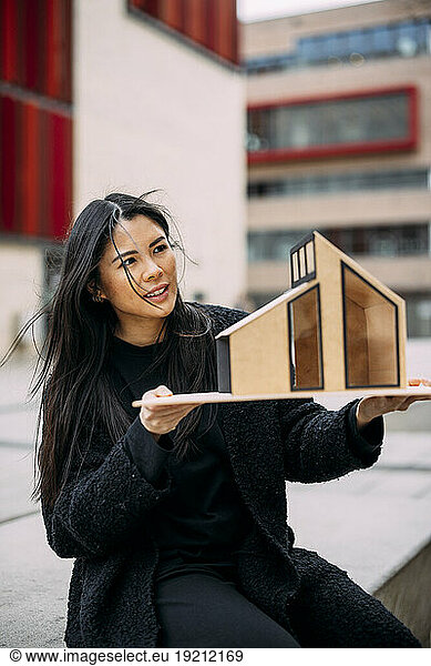 Architect analyzing architectural model house outside office building