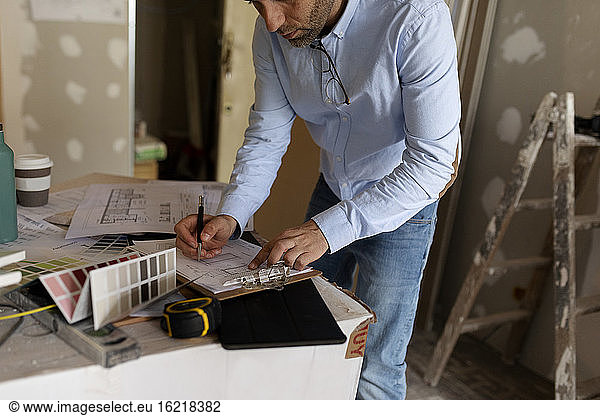 Architect at work with construction plan and colour swatch