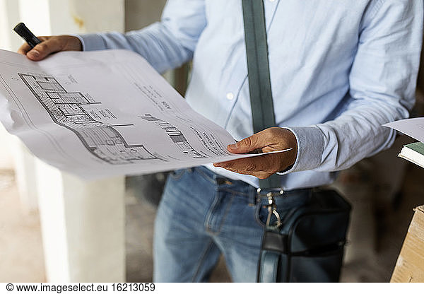 Architect holding plan in a house under construction