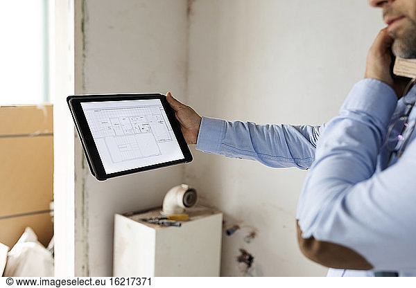 Architect holding tablet with construction plan