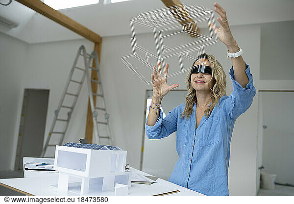 Architect wearing virtual reality simulator examining house model