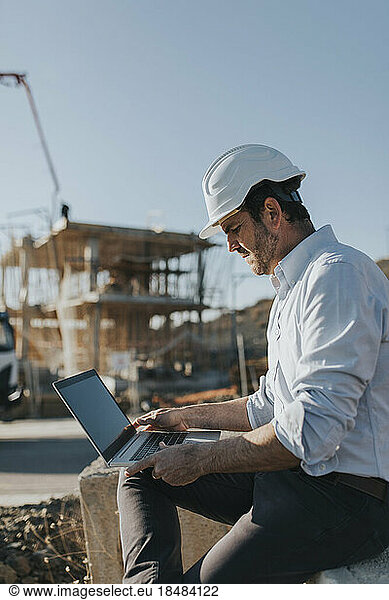 Architect working on laptop at construction site