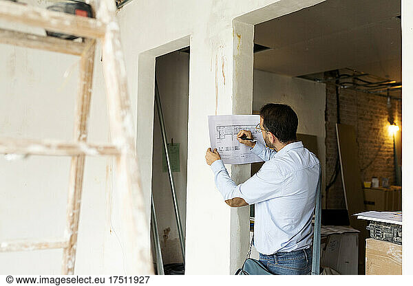 Architect working on plan in a house under construction
