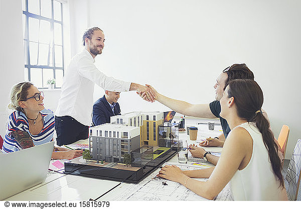 Architects handshaking in conference room meeting