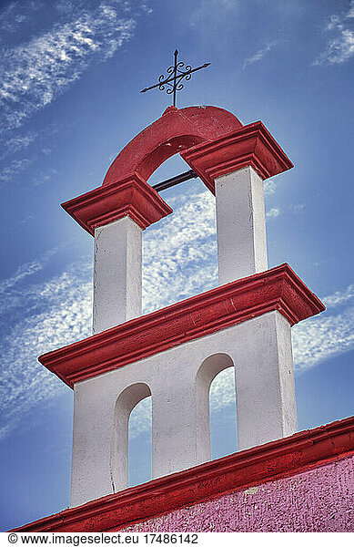 Architektonisches Detail  rot-weiße Farbe und Eisenkreuz auf einem Kirchendach in Cancun.