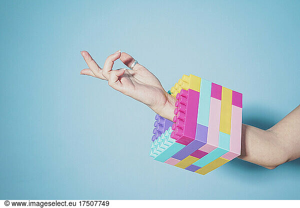 Arm of woman wearing colorful cube made of pastel colored toy blocks as bracelet