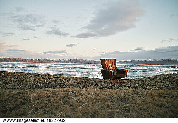 Armchair near waving sea at sundown