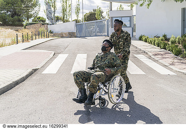 Armeeoffizier hilft einem anderen Soldaten  der im Rollstuhl sitzt