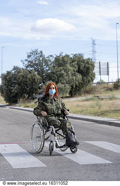 Army soldier sitting on wheelchair while wearing protective face mask