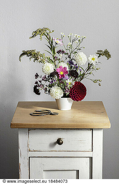 Arrangement of herbs and blooming autumn flowers on night table