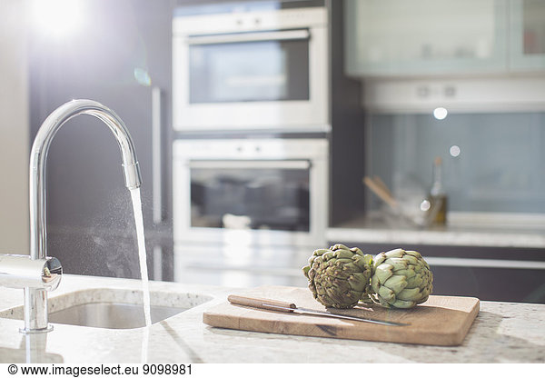 Artichokes on cutting board in modern domestic kitchen