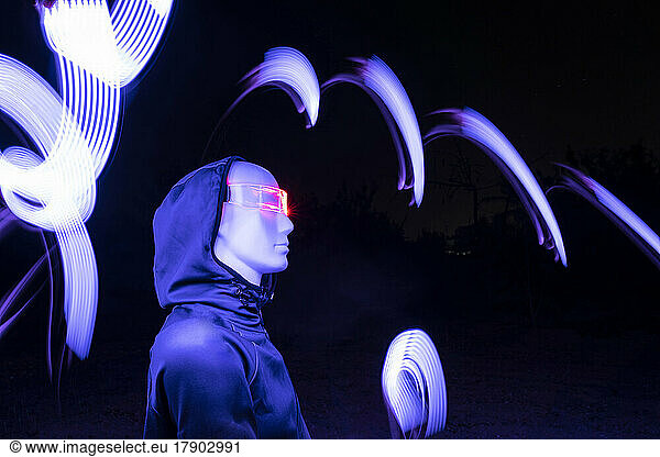 Artificial intelligence robot wearing futuristic eyeglasses standing by light trail