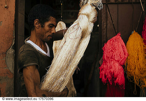 Artisan hanging silk thread to dry in workshop.