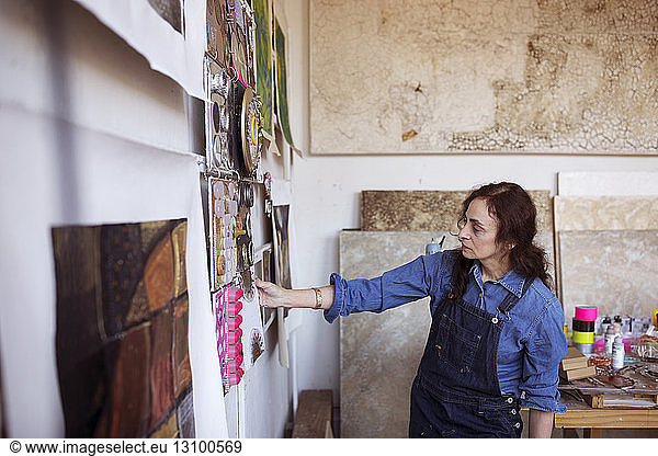 Artist looking paintings on wall in workshop