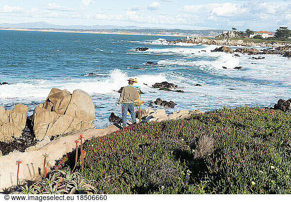 Artist painting landscape in the open air on the coastline of Monterey