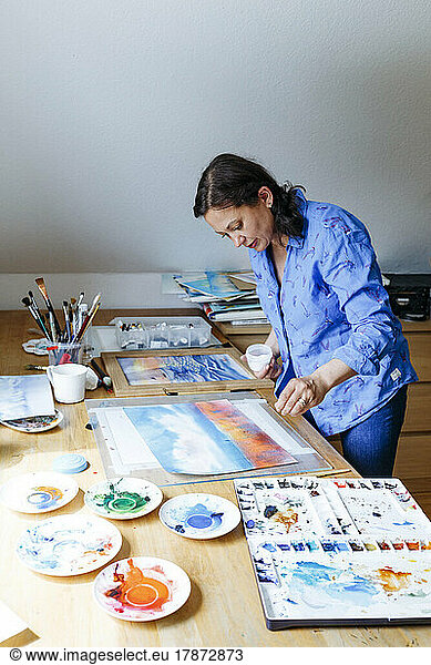 Artist sprinkling salt on watercolor painting at home