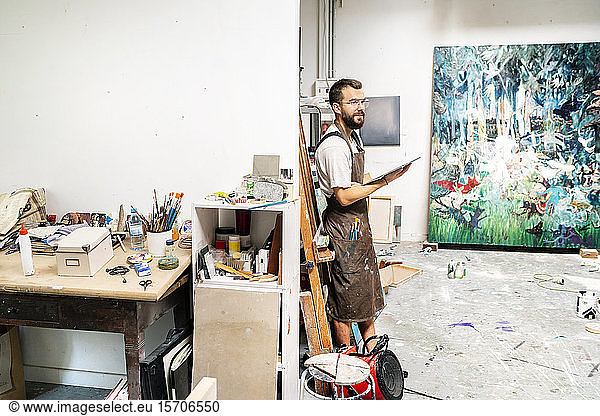 Artist standing in his studio  holdong digital tablet