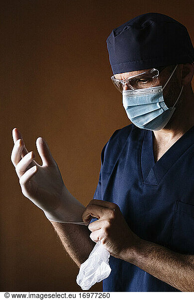 Arzt Chirurg zieht Latexhandschuhe an