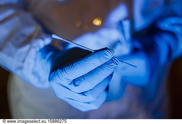 Arzt  der Schutzkleidung trägt  hält Virusabstrich-Test